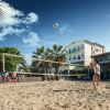 Partita di beach volley su sabbia, circondata da palme.