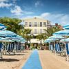Ombrelloni e sdraio blu su una spiaggia di fronte a un hotel.