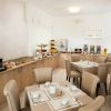 Sala colazione luminosa con tavoli apparecchiati.