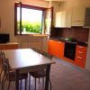 Cucina moderna con mobili arancioni, tavolo, sedie, e finestra aperta.