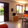 Soggiorno con divano arancione, tavolo da pranzo, cucina moderna, e porta aperta verso il giardino.