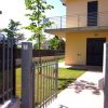 Ingresso di una casa con giardino e una porta. Cancelletto aperto verso un vialetto.