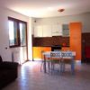 Cucina moderna con mobili arancioni, tavolo bianco e sedie grigie.