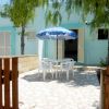 Cortile con tavolo, sedie bianche e ombrellone blu.