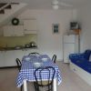 Cucina bianca con tavolo, sedie e divano blu.