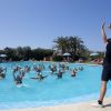 Istruttrice guida una lezione di aquagym in una piscina all'aperto.