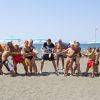 Gruppo di persone impegnate in un tiro alla fune sulla spiaggia.