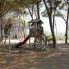 Bambini giocano su uno scivolo in un'area giochi tra alberi.