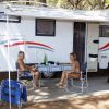 Camper con due persone sedute a un tavolo esterno.