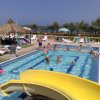 Piscina con scivolo giallo e bagnanti.