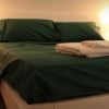Un letto matrimoniale con lenzuola verdi e asciugamani piegati.