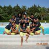 Gruppo sorridente davanti a una piscina con alberi.
