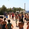Persone in cerchio giocano a palla sulla spiaggia.