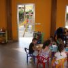 Bambini dipingono a un tavolo in un'aula colorata con finestre che mostrano un parco giochi.