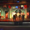 Spettacolo teatrale con attori che ballano sul palco.
