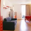 Salotto luminoso con tavolo rosso, divano blu e accesso a un balcone.
