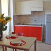 Piccola cucina moderna con mobili rossi, un tavolo apparecchiato e un mazzo di girasoli.