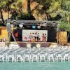 Teatro all’aperto con sedie bianche e palco.