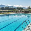Una piscina con scale metalliche, ombrelloni, e montagne sullo sfondo.