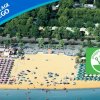 Spiaggia con ombrelloni e mare, vicino a una pineta.