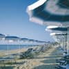 Spiaggia con ombrelloni blu e lettini.