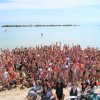Gruppo di persone in costume su una spiaggia che esultano.