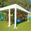 Parco giochi coperto con scivoli e strutture su prato artificiale.