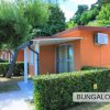 Bungalow arancione con veranda e siepi.