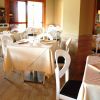 Sala da pranzo con tavoli apparecchiati, sedie bianche e ambiente luminoso.