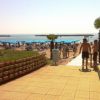 Spiaggia con ombrelloni blu, persone e palme vicino al mare.