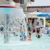 Piscina con getto d'acqua e persone che nuotano e si divertono.