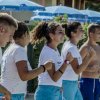 Un gruppo di persone in tenuta sportiva allegre e che camminano all'aperto vicino a ombrelloni blu.