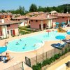 Una piscina circondata da lettini e ombrelloni blu, con villette sullo sfondo.