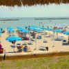 Una spiaggia con ombrelloni blu e sdraio, vista sul mare con barriere di frangimento.