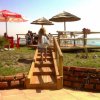 Una passerella in legno conduce a una terrazza con sedie e ombrelloni vista mare.