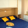 Camera con letto matrimoniale, cuscini gialli, mobili in legno chiaro, volantini sopra al letto.