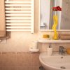Bagno con specchio, lavandino, termosifone e decorazioni, tra cui fiori rossi in un vaso giallo.