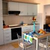 Cucina moderna con tavolo apparecchiato, fiori, frutta e divano blu visibili sullo sfondo.