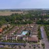 Vista aerea di un complesso residenziale con piscine, circondato da verde e altre abitazioni.