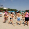 Persone giocano in cerchio su una spiaggia soleggiata.