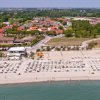 Spiaggia con ombrelloni e villette sullo sfondo.