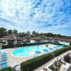 Un complesso residenziale con piscina, molte sdraio blu e cielo nuvoloso.