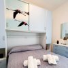 Stanza con letto matrimoniale, armadio con immagini, specchio e cassetti.