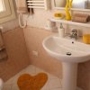 Bagno con lavello, specchio, accessori beige e gialli, e tappetino a forma di cuore.
