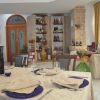 Sala da pranzo con tavoli apparecchiati e scaffali di bottiglie.