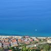 Vista aerea di una costa con case e mare azzurro.