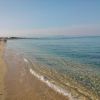 Spiaggia con sabbia dorata e mare calmo, poche persone in lontananza.
