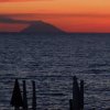 Tramonto sul mare con un'isola in lontananza.