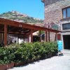Edificio in pietra con veranda e piantine, colline sullo sfondo.