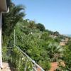 Balcone con vista panoramica tra palme e colline verdi.